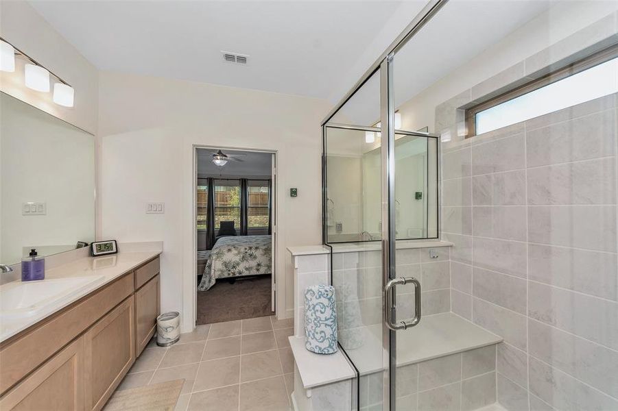 Bathroom with tile patterned floors, ceiling fan, vanity, and an enclosed shower