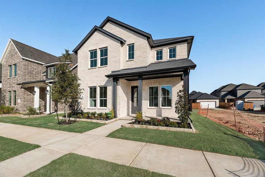 View of front facade featuring a porch, a front yard, and brick siding
