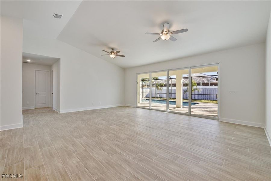 Spare room featuring vaulted ceiling, wood tiled floors, and ceiling fan