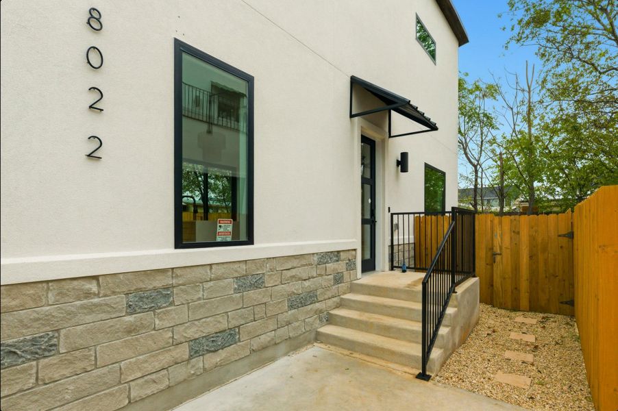 Doorway to property with stucco siding, a gate, and stone siding Doorway to property with stucco siding, a gate, and stone siding