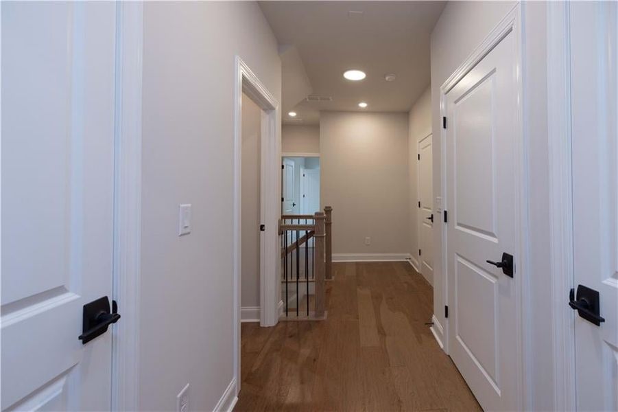 Hallway featuring recessed lighting, an upstairs landing, and wood finished floors