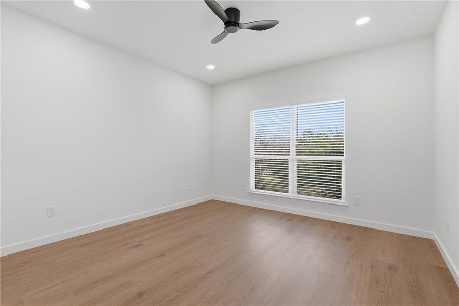 Bright room featuring light wood-finish flooring and a central window with horizontal blinds