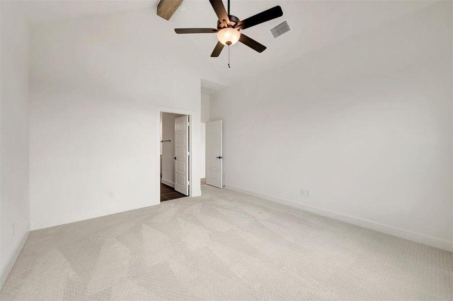 Spacious room featuring vaulted ceilings, light-toned carpeting, and a ceiling fan with integrated lighting