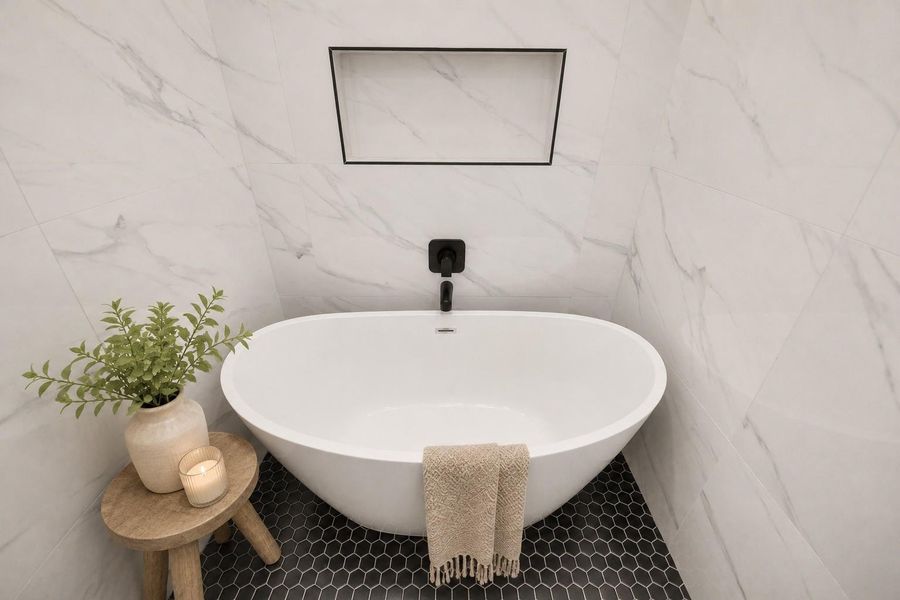 Elegant freestanding soaking tub surrounded by floor-to-ceiling marble-look tile, creating a serene spa-inspired retreat.