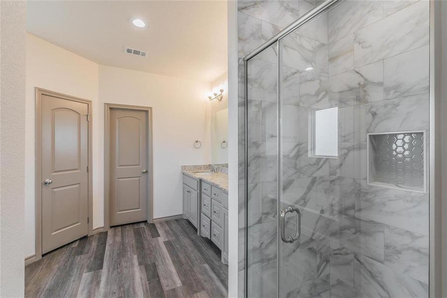 Bathroom with double vanity, a marble finish shower, recessed lighting, and dark wood-type flooring