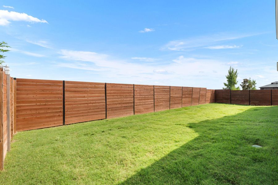 Generous grassy expanse enclosed by a contemporary wooden privacy fence, offering an ideal space for outdoor enjoyment.