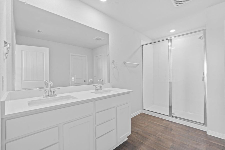 Bathroom with a stall shower, dark wood-type flooring, double vanity, and recessed lighting Bathroom with a stall shower, dark wood-type flooring, double vanity, and recessed lighting