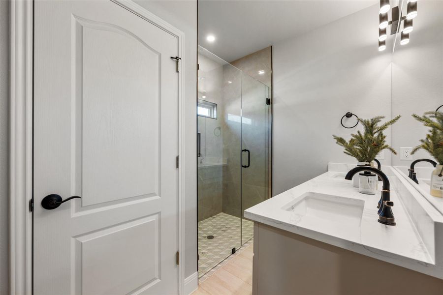 Full bathroom with double vanity, a stall shower, and recessed lighting