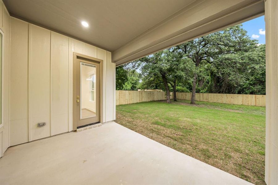 Covered patio with a concrete surface, recessed lighting, and direct access to the expansive backyard featuring a new wood privacy fence and mature trees