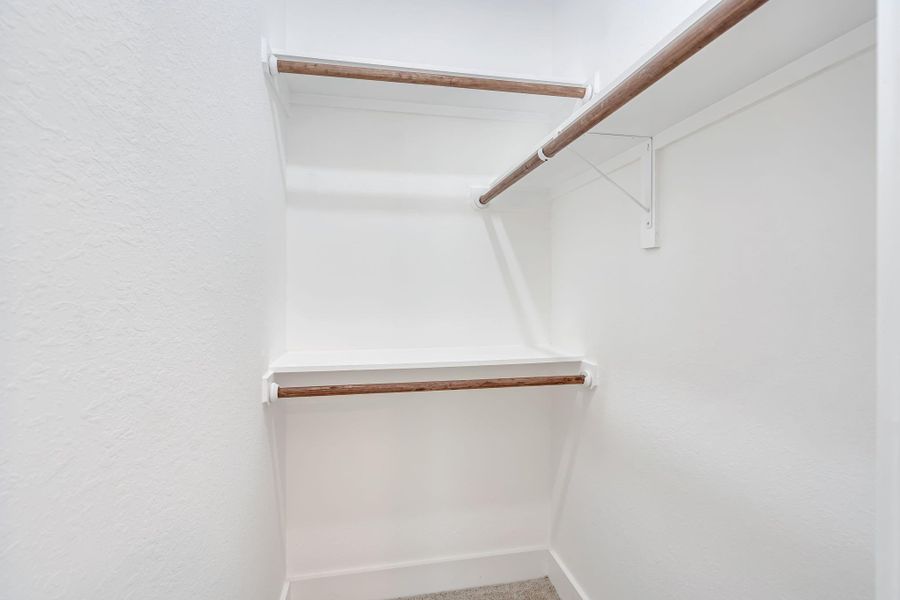 Closet for the third upstairs bedroom featuring built-in hanging space and shelving for organized storage.