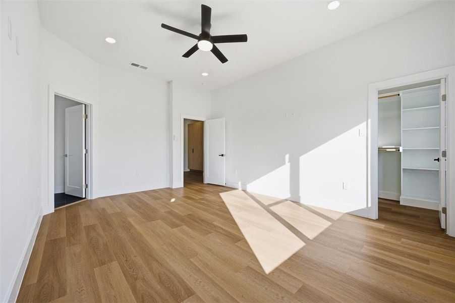 Primary Bedroom features recessed lighting and ceiling fan with light fixture. Walk-in closet provides
built-in shelving and organization. Doorway connects directly to the ensuite bathroom. Vinyl flooring extends throughout.