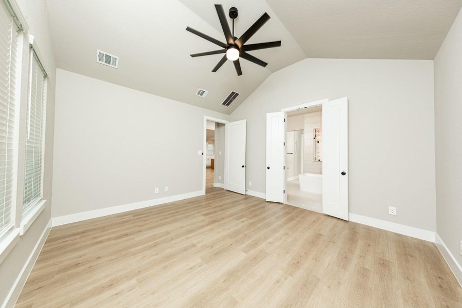 Relax and unwind after a long day in this impressive primary suite! This generously sized room offers the same wood-look flooring, neutral-toned paint, cathedral ceilings with a ceiling fan, and large windows for added comfort and tranquility. Relax and unwind after a long day in this impressive primary suite! This generously sized room offers the same wood-look flooring, neutral-toned paint, cathedral ceilings with a ceiling fan, and large windows for added comfort and tranquility.