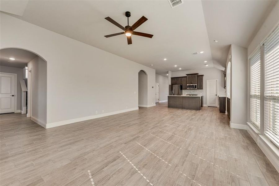 Unfurnished living room featuring arched walkways, recessed lighting, light wood-style floors, and a ceiling fan Unfurnished living room featuring arched walkways, recessed lighting, light wood-style floors, and a ceiling fan