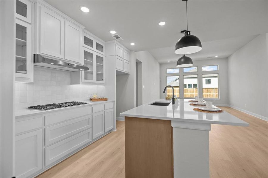 Contemporary kitchen featuring white cabinetry, a gas cooktop with a stainless steel range hood, and a white subway tile backsplash Contemporary kitchen featuring white cabinetry, a gas cooktop with a stainless steel range hood, and a white subway tile backsplash