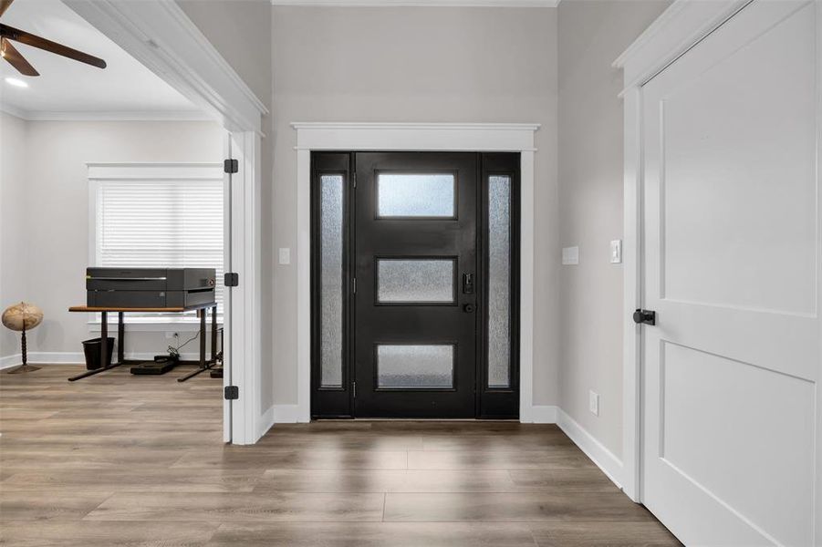 Entrance foyer featuring hardwood / wood-style flooring, ceiling fan, and ornamental molding