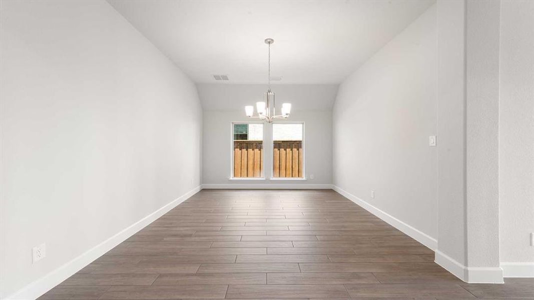 Unfurnished dining area featuring vaulted ceiling, dark hardwood / wood-style floors, and a notable chandelier