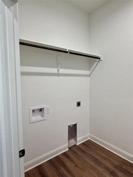 Dedicated laundry area featuring wood-finish flooring, white baseboards, and a built-in shelf with hanging rod