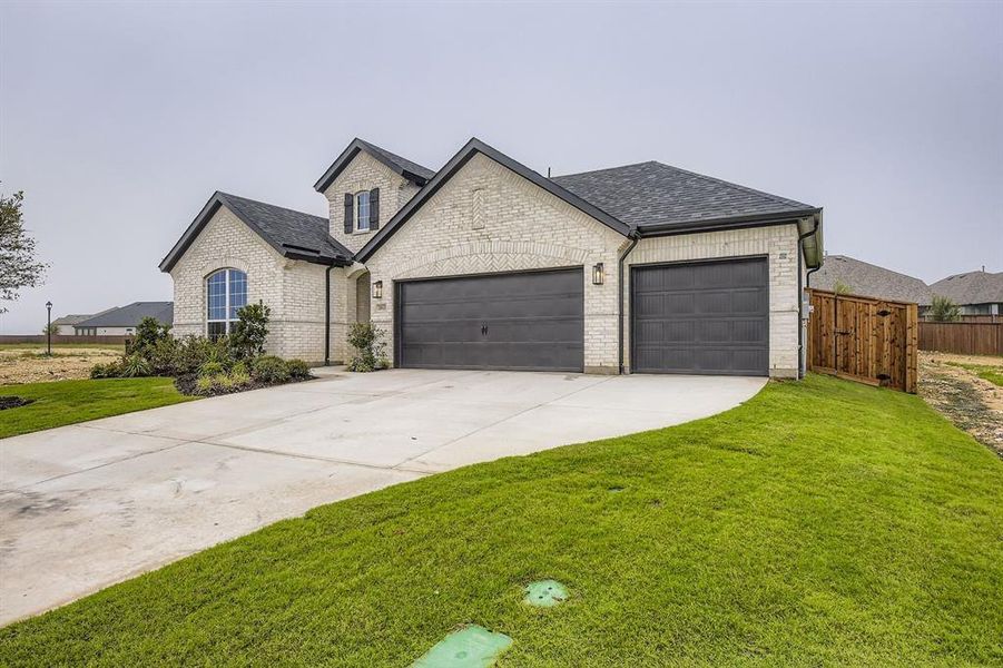 French provincial home featuring concrete driveway, brick siding, roof with shingles, and a garage