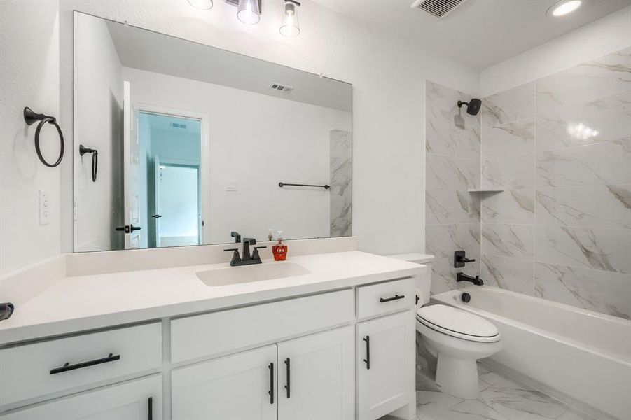 Full bath featuring visible vents, toilet, bathing tub / shower combination, marble finish floor, and vanity