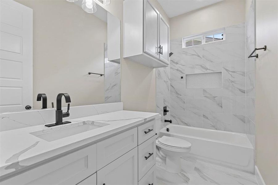 Full bathroom with toilet, vanity, and tiled shower / bath combo