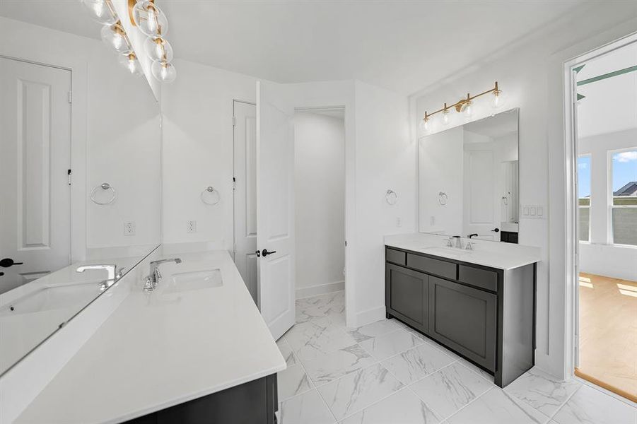 Full bath with two vanities and light marble finish floors