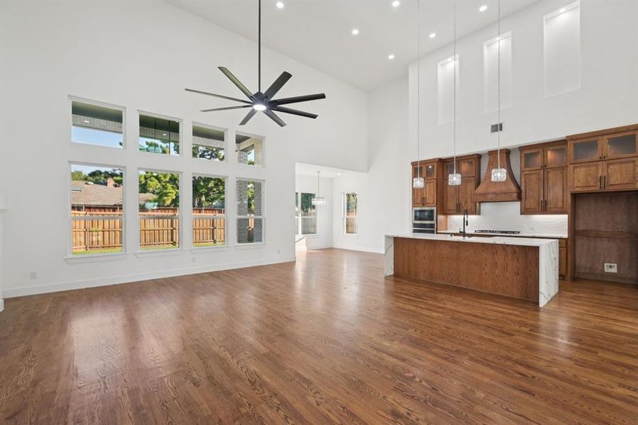 Kitchen featuring open floor plan, stained brown cabinets, pendant lighting, a kitchen island with sink, and recessed lighting