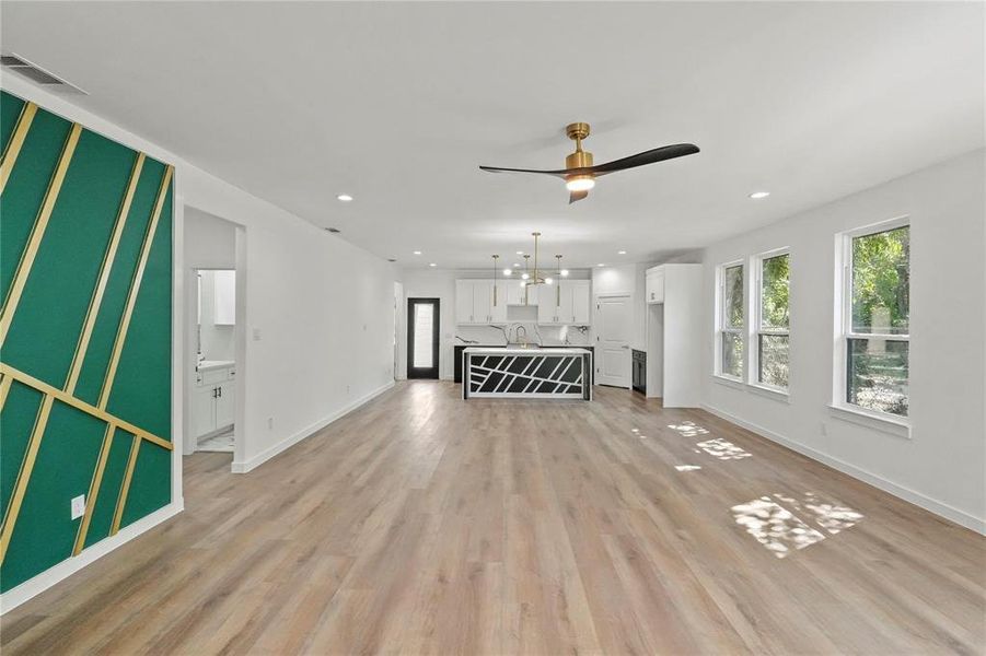 Unfurnished living room with ceiling fan, sink, and light hardwood / wood-style flooring