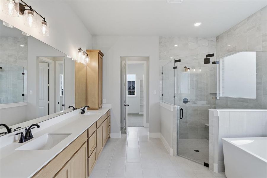 Full bath with double vanity, a stall shower, a freestanding bath, light tile patterned floors, and recessed lighting