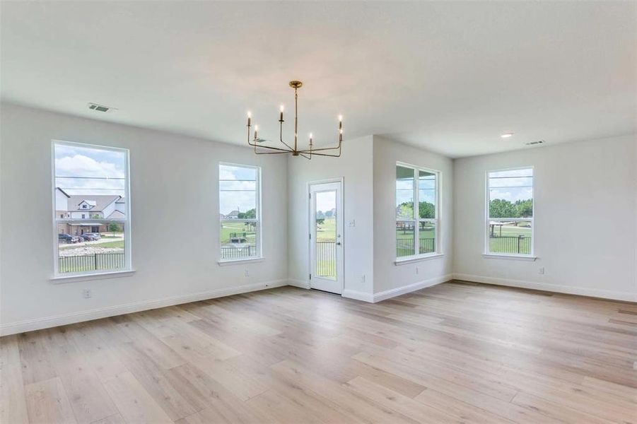 Spare room featuring a chandelier and light wood-style floors Spare room featuring a chandelier and light wood-style floors