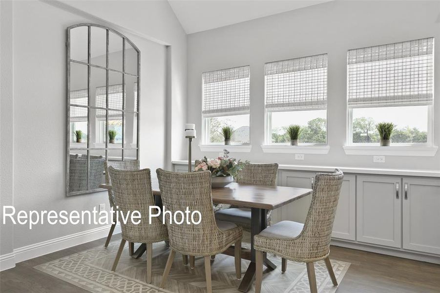 Dining area featuring vaulted ceilings and a series of three windows Dining area featuring vaulted ceilings and a series of three windows