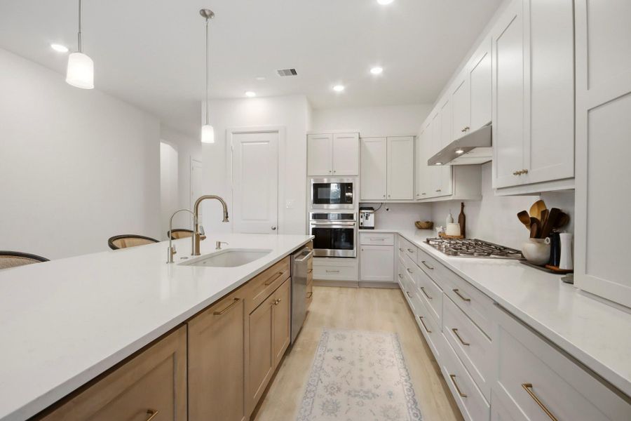 Contemporary kitchen appointed with a generous island and sink, stylish pendant lighting, and abundant white cabinetry for a clean, functional design.
