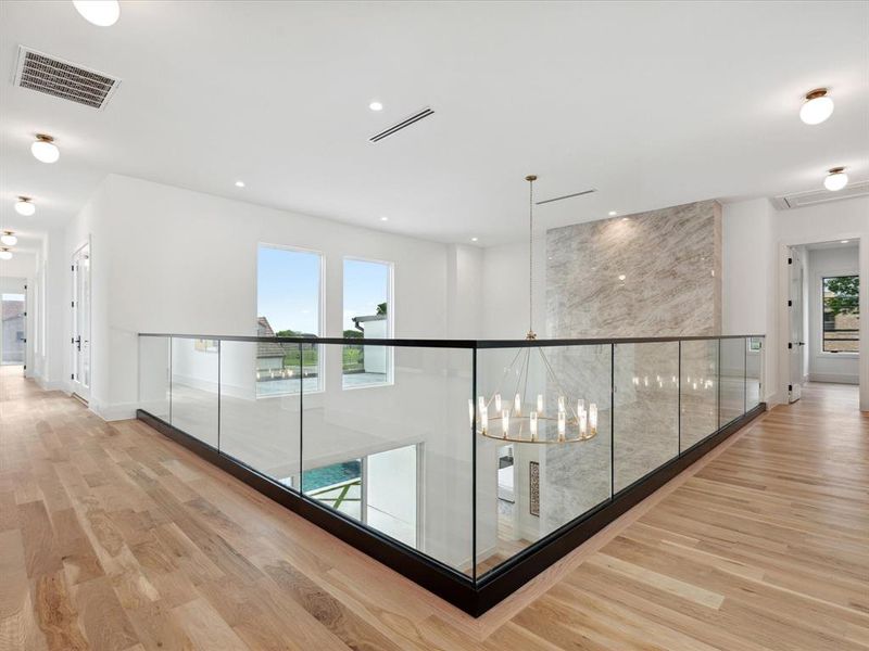 Hall featuring a notable chandelier, plenty of natural light, and light hardwood / wood-style flooring