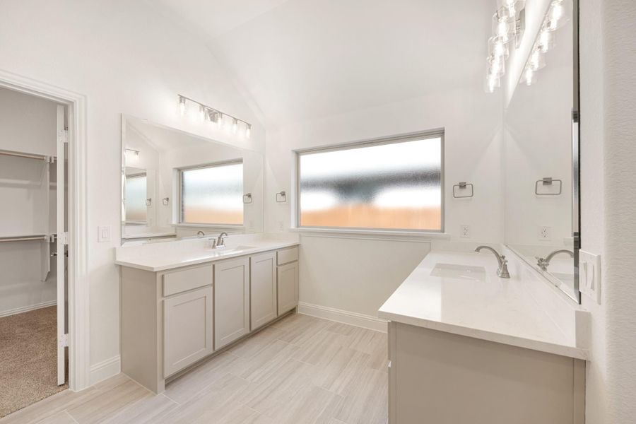 Master bathroom with double vanity, soaking tub, white countertops, and walk-in closet access
