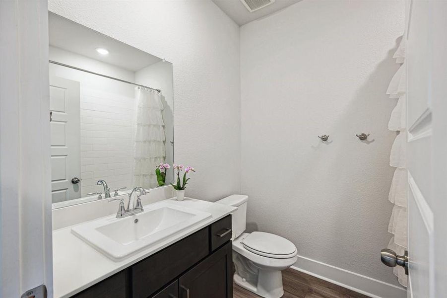 Bathroom with vanity, curtained shower, and toilet