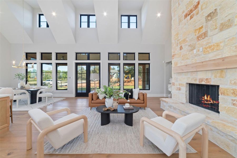 Stunning living room with soaring ceilings, expansive windows, grand stone fireplace, and abundant natural light.