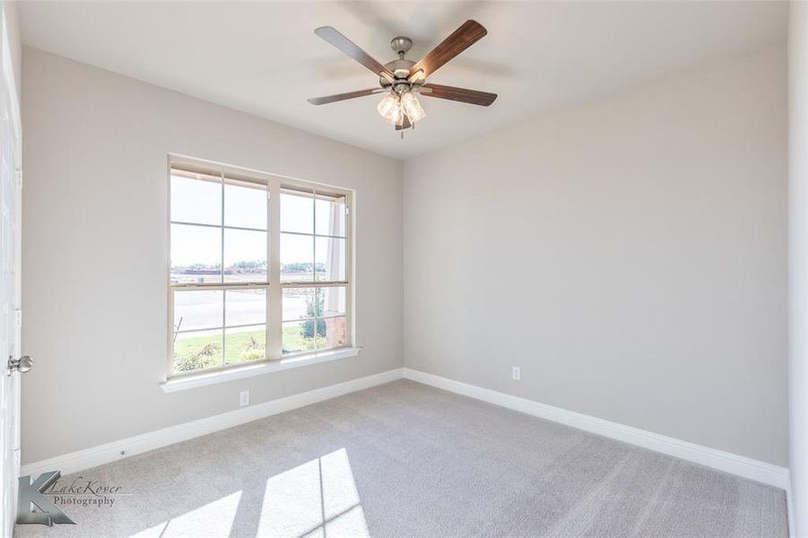 Empty room featuring carpet, a water view, and a ceiling fan