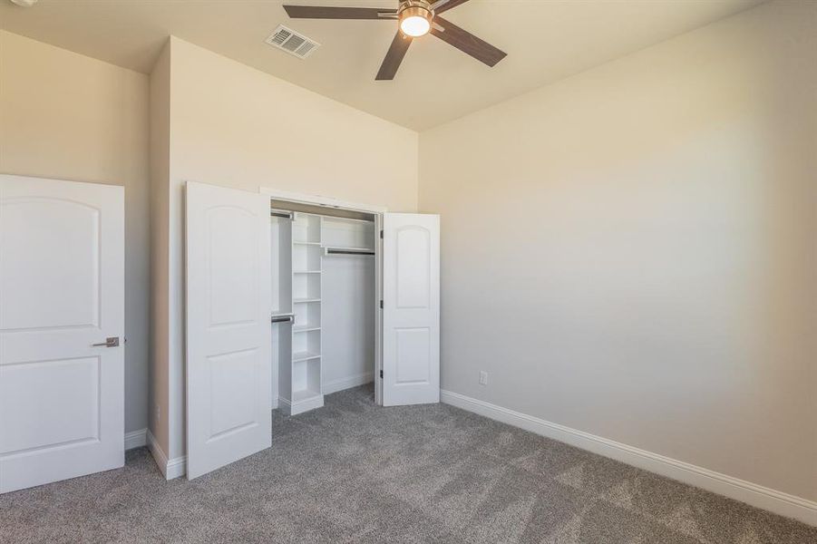 Unfurnished bedroom with ceiling fan, a closet, and carpet