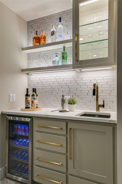 Indoor bar with backsplash, open shelves, wine cooler, and light stone countertops Indoor bar with backsplash, open shelves, wine cooler, and light stone countertops