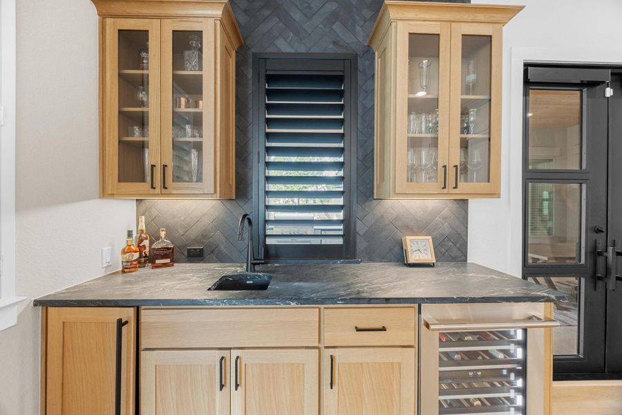 Indoor wet bar featuring tasteful backsplash and ice maker and beverage cooler