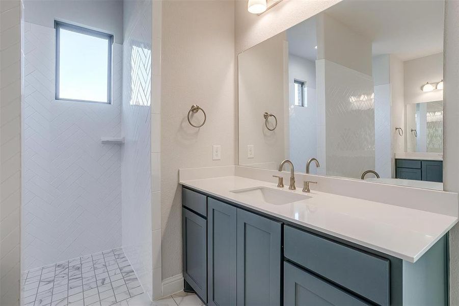 Bathroom featuring tiled shower, vanity, and tile patterned floors