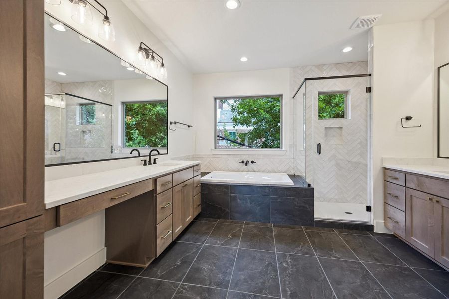 A spa-like primary suite featuring a lavish 5-piece bath with dual vanities, a deep soaking tub, and a separate glass-enclosed shower leading into a spacious walk-in closet designed for extensive wardrobes.