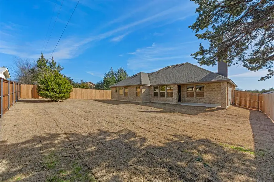 Rear view of house with a fenced backyard, a chimney, a patio area, brick siding, and a shingled roof