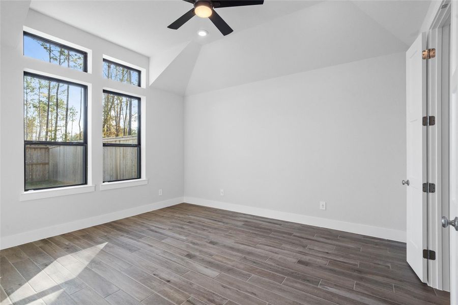 Retreat to this bright and airy primary bedroom, a serene sanctuary designed for ultimate relaxation and comfort. Vaulted ceilings, large windows, tile plank flooring, and modern ceiling fan give this room a peaceful space to come home to. Retreat to this bright and airy primary bedroom, a serene sanctuary designed for ultimate relaxation and comfort. Vaulted ceilings, large windows, tile plank flooring, and modern ceiling fan give this room a peaceful space to come home to.