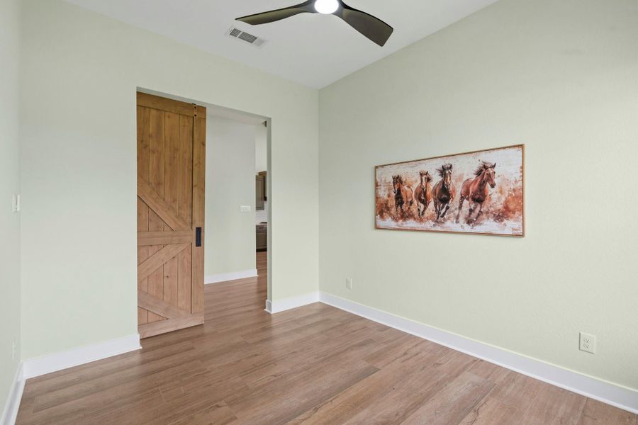 The Study, located directly off the Foyer, is accessible through a stately barn door. Overhead, an upgraded three-blade ceiling fan serves as both a stylish focal point and a functional enhancement, ensuring the room remains comfortably illuminated and well-circulated year-round.
