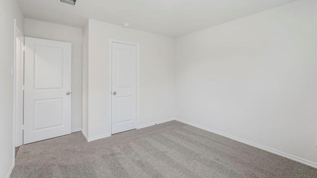 Neutral wall color, grey carpet flooring, white trim, and two white panel doors