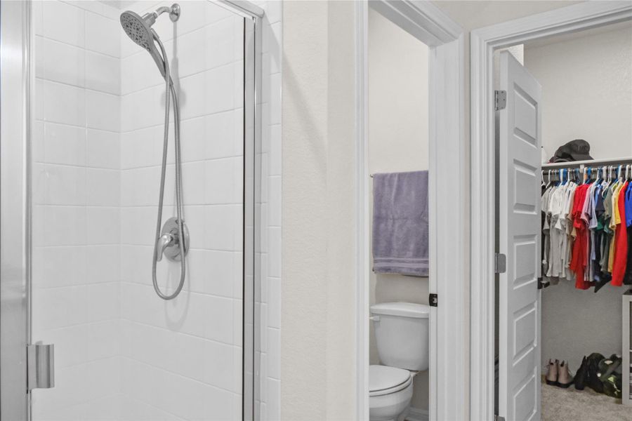 Bathroom featuring a walk in closet and a shower stall