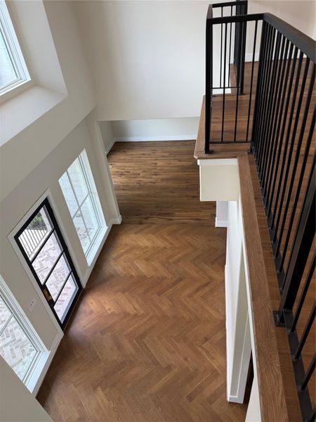 Moving to the second floor - the grand two story entry features custom herringbone wood floor design and several large windows...small balcony overlooks front door