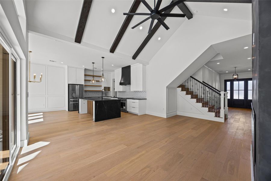 Kitchen featuring hanging lights, open floor plan, an island with sink, and white cabinetry Kitchen featuring hanging lights, open floor plan, an island with sink, and white cabinetry
