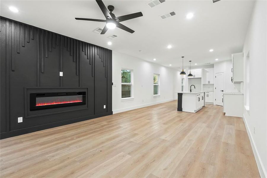Unfurnished living room featuring a glass covered fireplace, a ceiling fan, recessed lighting, and light wood-style floors Unfurnished living room featuring a glass covered fireplace, a ceiling fan, recessed lighting, and light wood-style floors