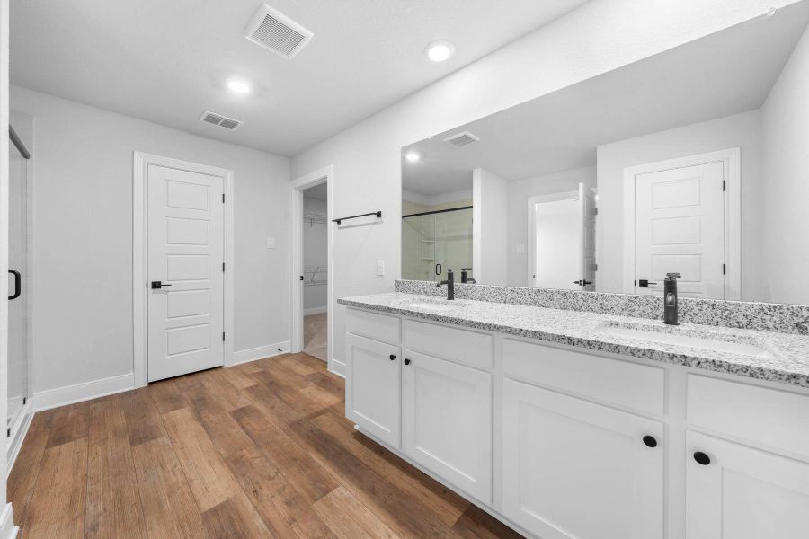 Double vanity with stone counters and rich wood flooring defines this contemporary bathroom. Double vanity with stone counters and rich wood flooring defines this contemporary bathroom.